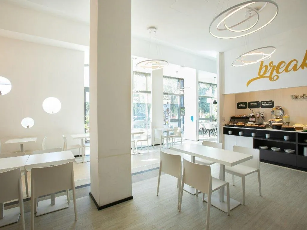 Sala colazione luminosa con tavoli bianchi, lampadari di design e buffet