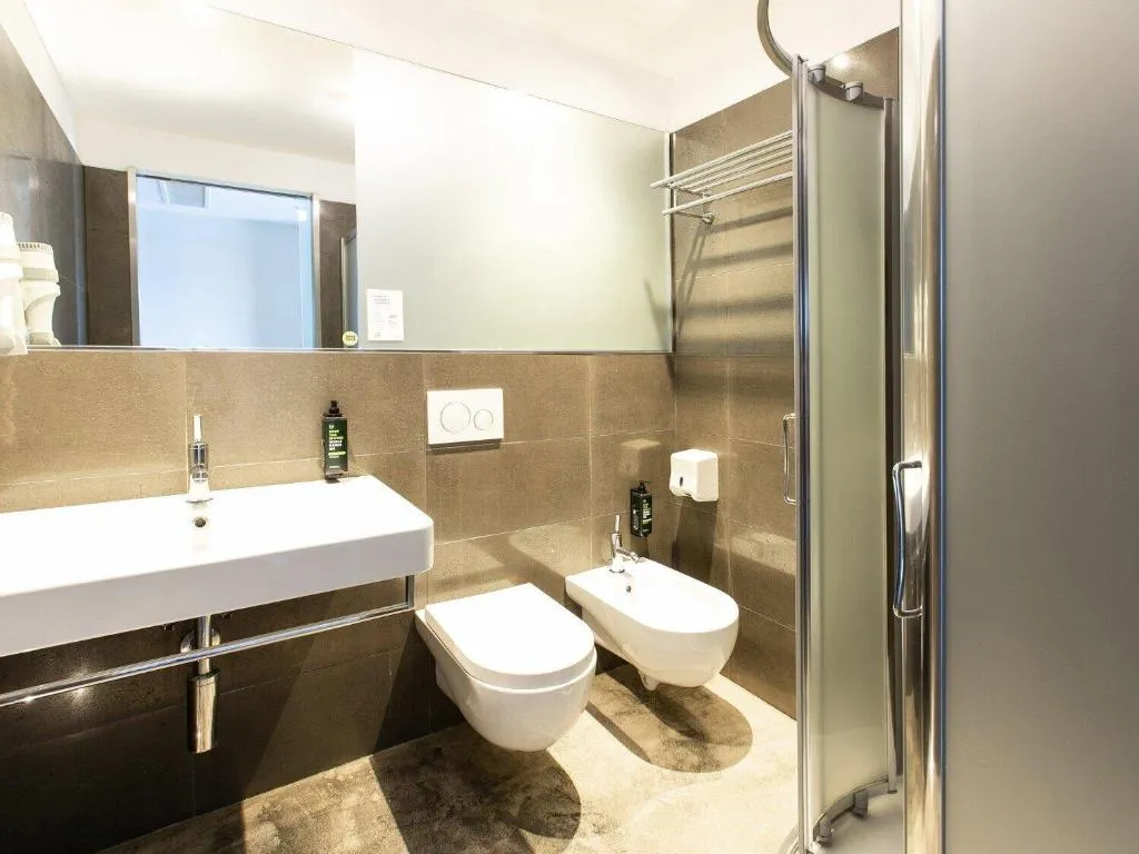 Bagno moderno con lavabo, WC, bidet e doccia con pareti piastrellate