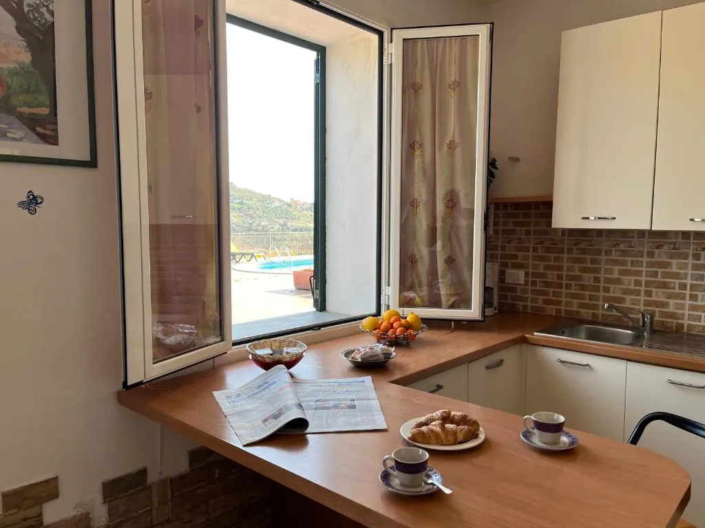 Cucina con finestra aperta affacciata sulla piscina e colazione sul piano in legno
