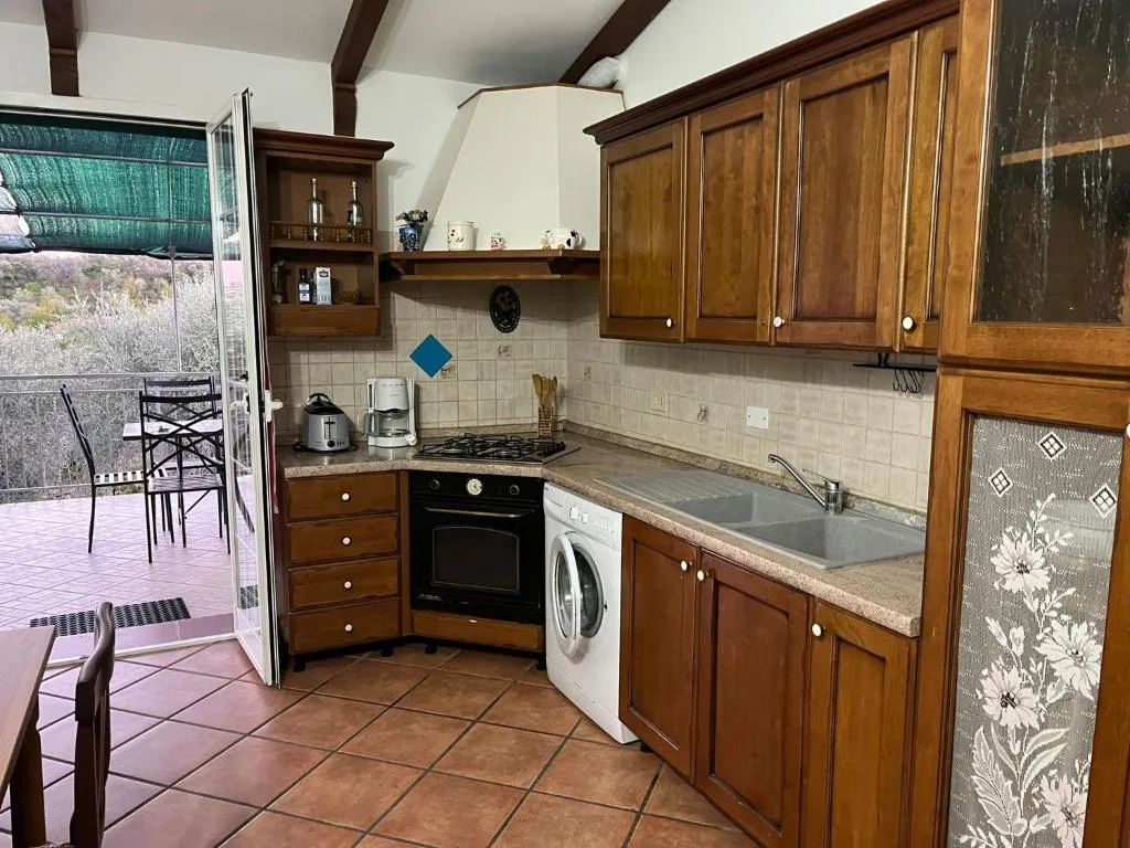 Cucina in legno con porta aperta sulla terrazza e vista sul verde