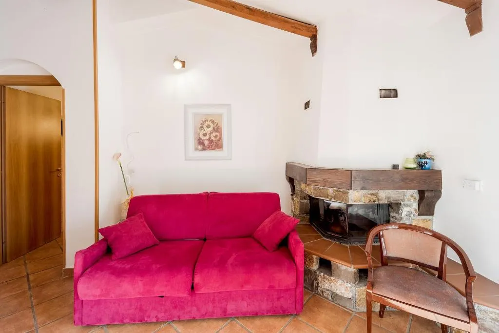 Soggiorno con divano fucsia e camino in pietra angolare