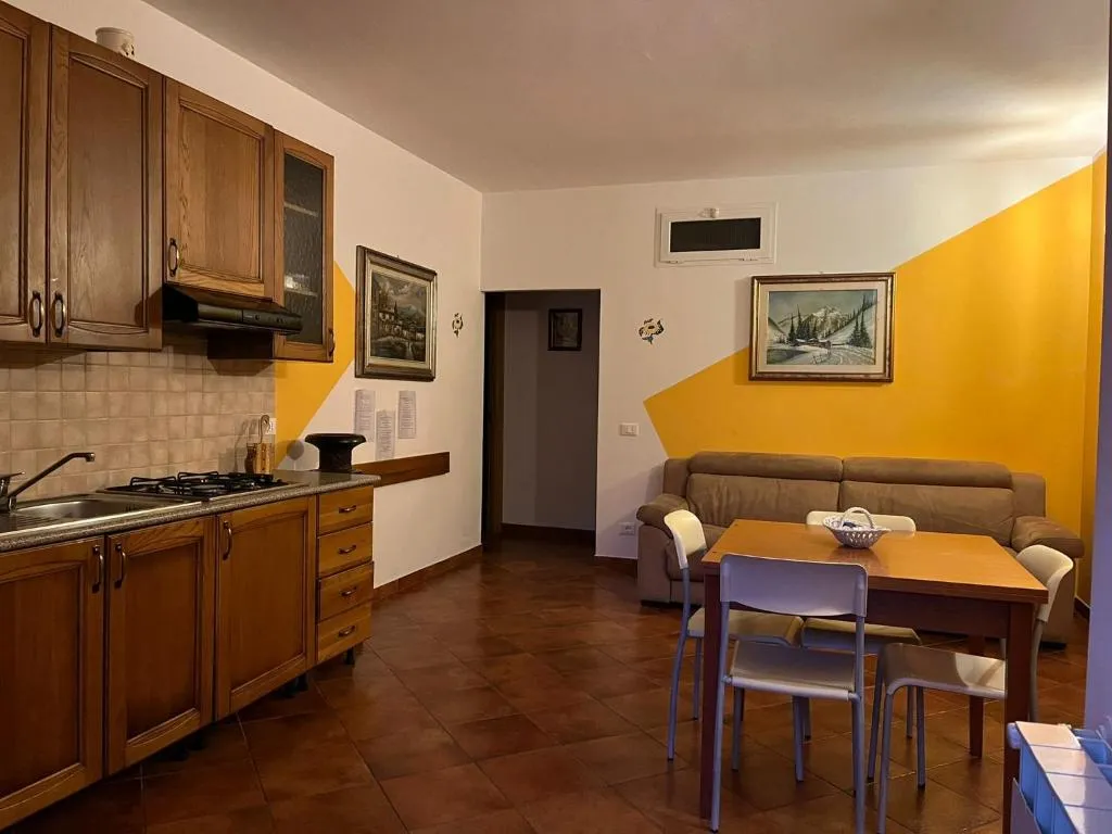Soggiorno con angolo cottura in legno, divano e pareti decorate in giallo