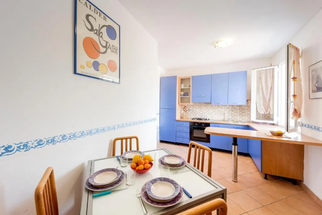 Soggiorno con tavolo apparecchiato e cucina con mobili blu