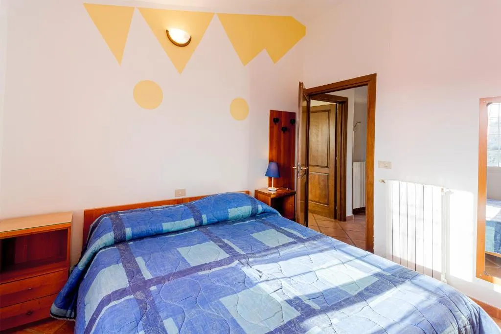 Camera da letto matrimoniale con pareti decorate gialle e blu e armadio in legno