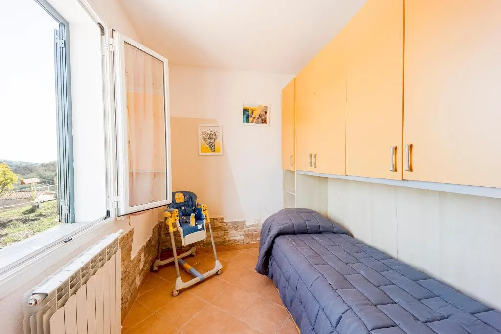 Cameretta con letto singolo, mobili gialli, seggiolone e finestra luminosa
