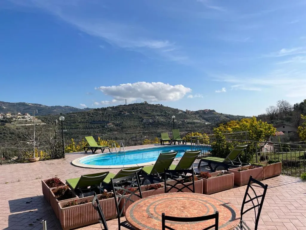 Area piscina con tavolo, lettini e fioriere affacciata sul paesaggio collinare