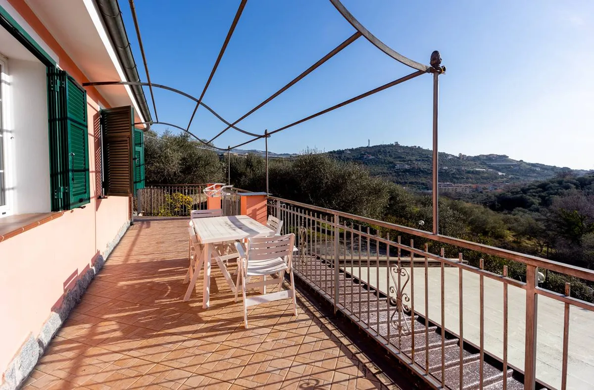 Ampia terrazza in cotto con tavolo e sedie bianche e vista panoramica sulle colline