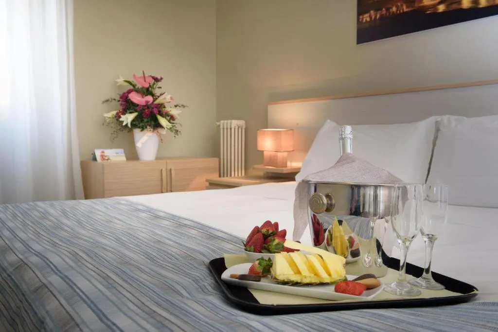 Letto con vassoio di frutta, spumante e fiori per accoglienza romantica