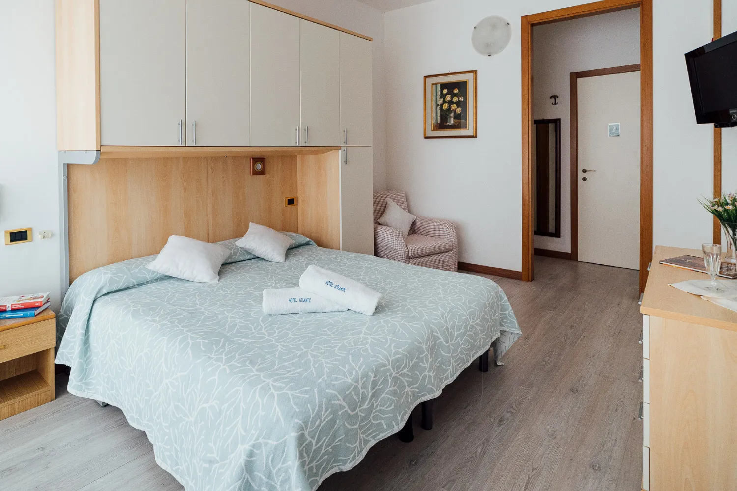 Camera spaziosa con letto matrimoniale, armadio, poltrona e asciugamani Hotel Atlantic