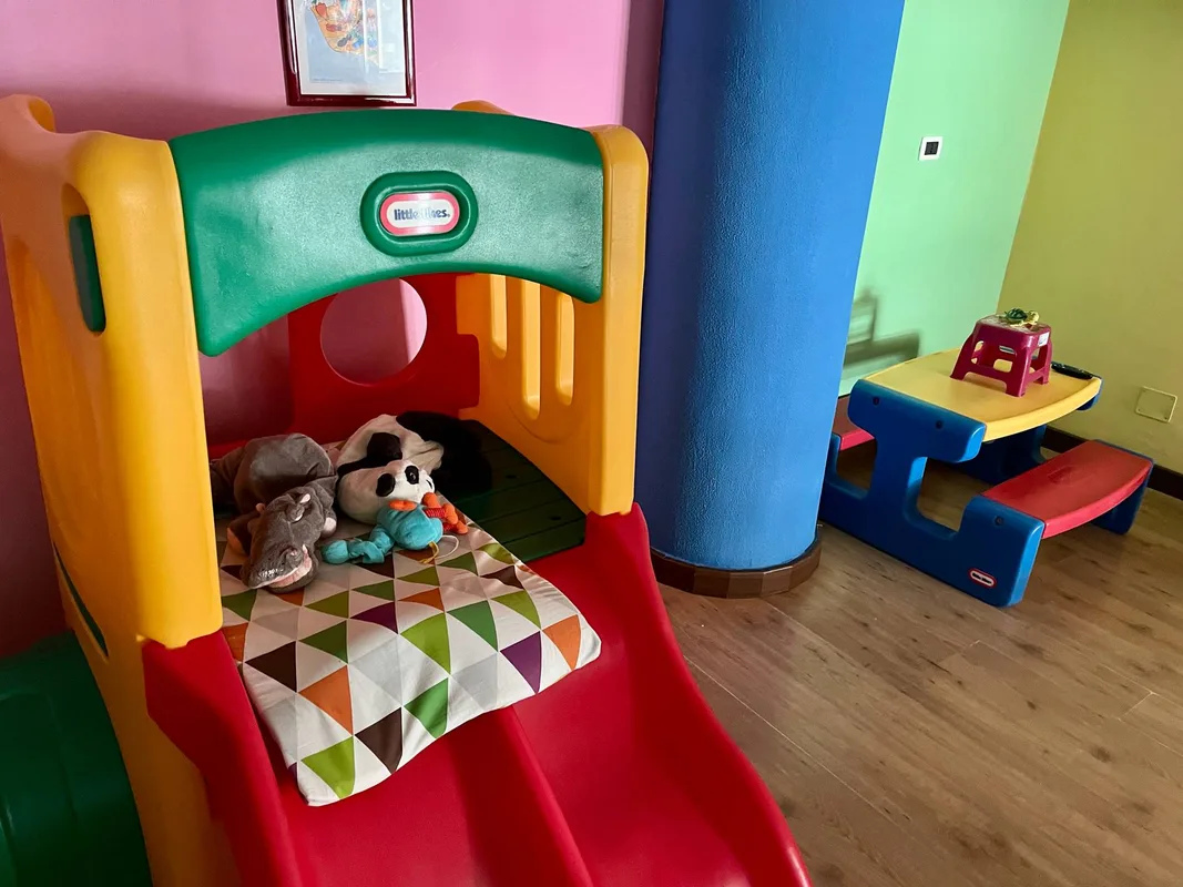 Angolo dell'area giochi con scivolo, peluche e tavolino colorato