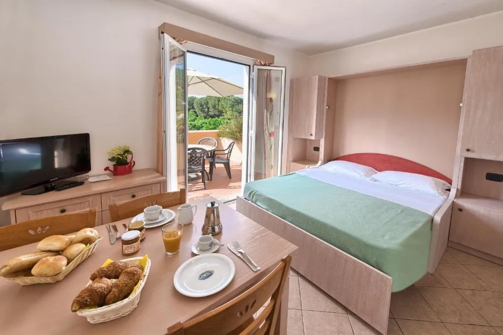 Monolocale con letto matrimoniale, tavolo apparecchiato per la colazione e accesso alla terrazza