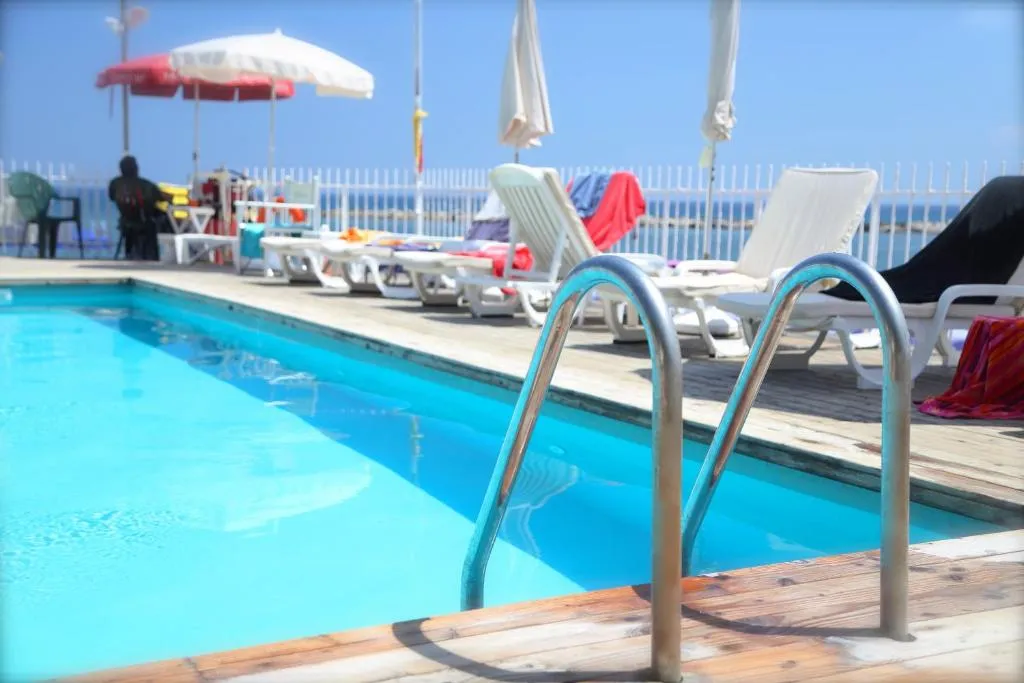 Dettaglio della piscina con scaletta, lettini e ombrelloni vista mare