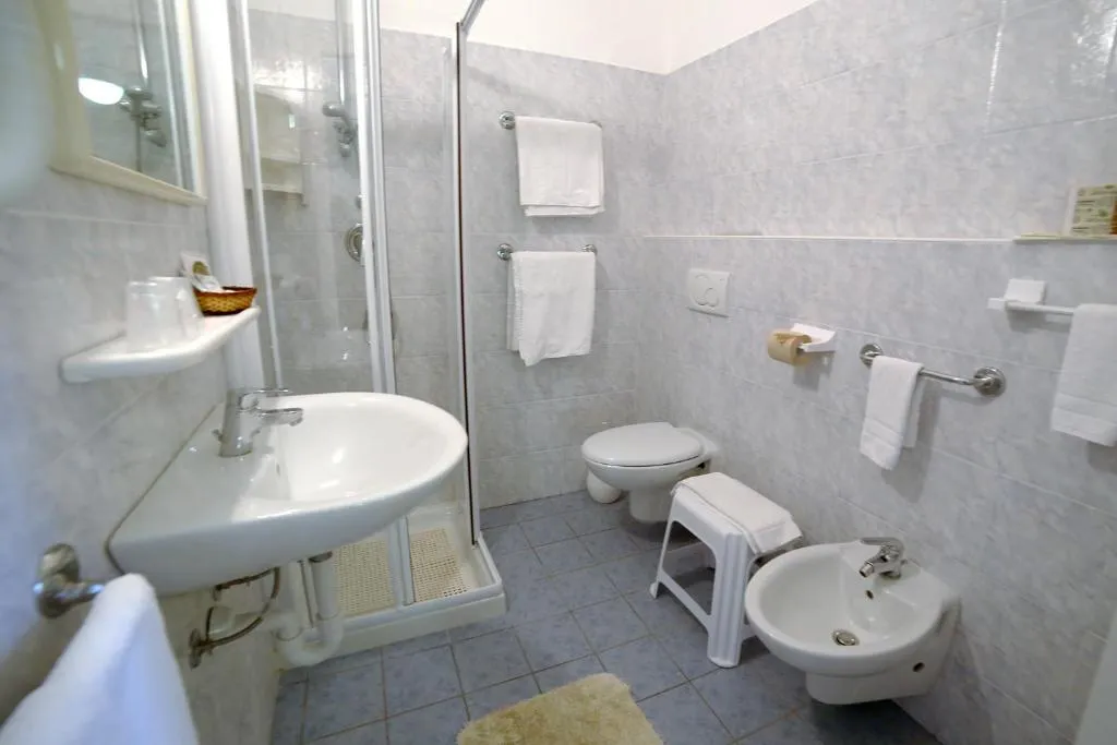 Bagno con doccia, lavabo, WC e bidet rivestito in piastrelle chiare