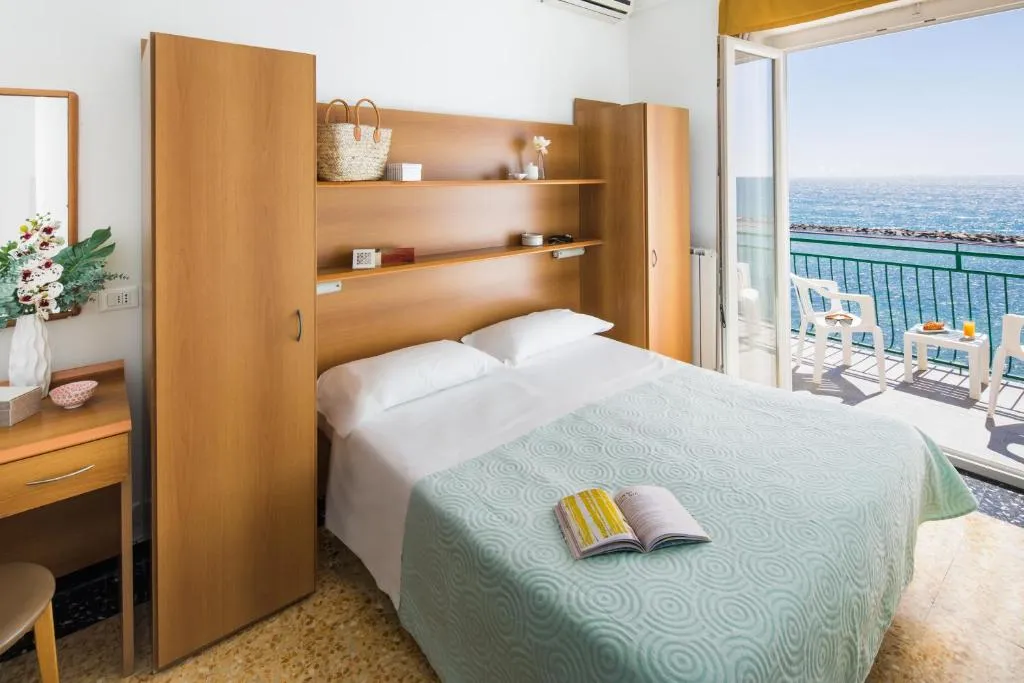 Camera con letto matrimoniale, armadi in legno e balcone affacciato sul mare
