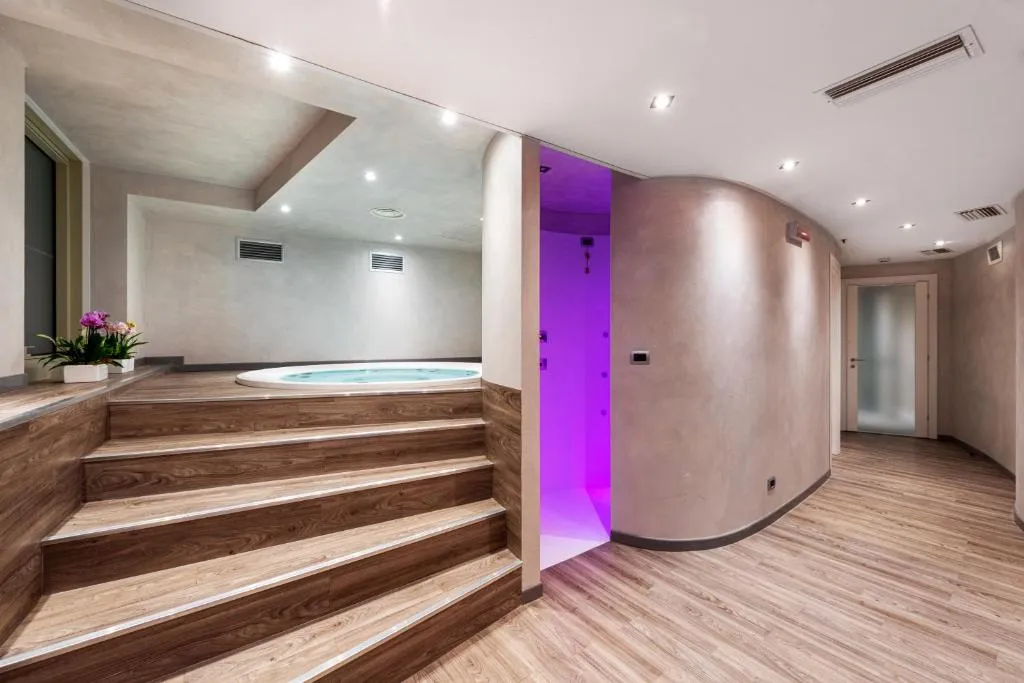 Area benessere con vasca idromassaggio incassata, gradini in legno e doccia emozionale viola