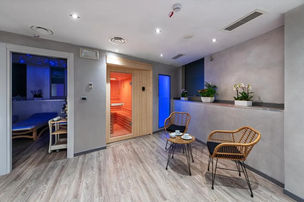 Area spa con sauna in legno, cromoterapia e poltrone in vimini con tavolino