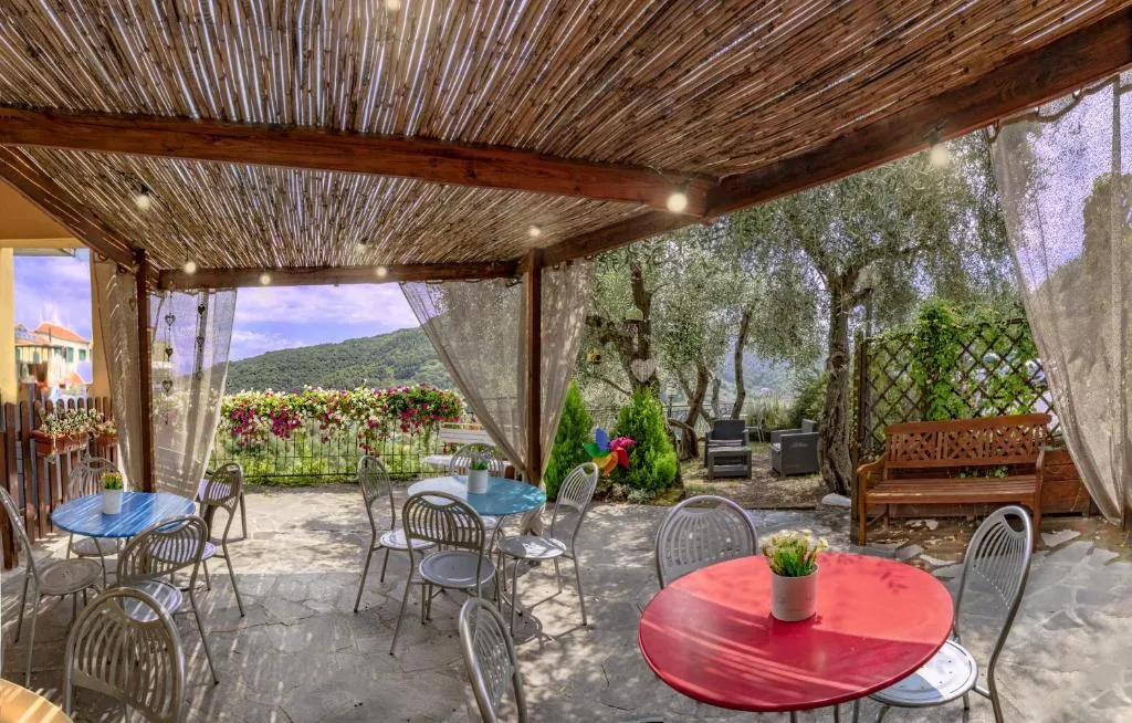 Area relax esterna sotto pergolato in canne con tavoli colorati e vista panoramica