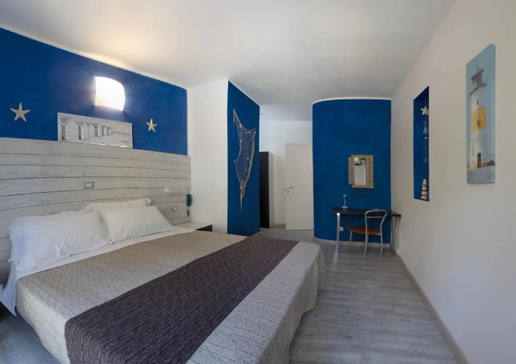 Camera con parete blu, testiera in legno e angolo scrivania