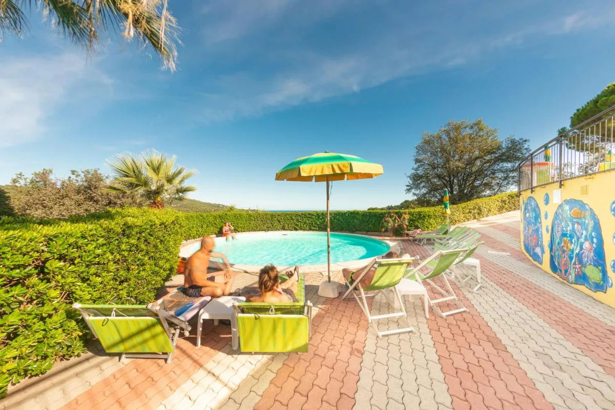 Ospiti in relax a bordo piscina con ombrellone e lettini verdi