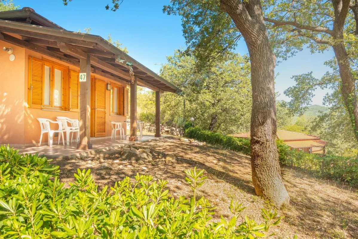 Bungalow con veranda, tavoli e sedie immerso nel verde