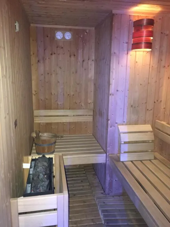 Sauna in legno con panche, secchio e luce soffusa