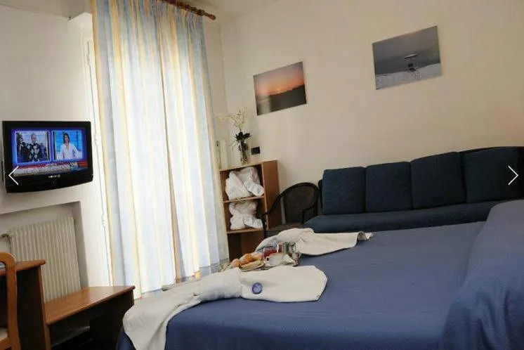 Camera con letto matrimoniale blu, divano, TV e quadri marini alle pareti