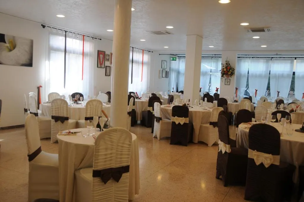 Sala ristorante allestita per eventi con tavoli rotondi e sedie rivestite in bianco e marrone