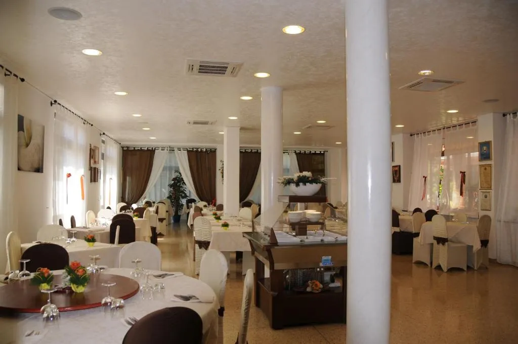 Sala ristorante elegante con tavoli apparecchiati, colonne bianche e zona buffet