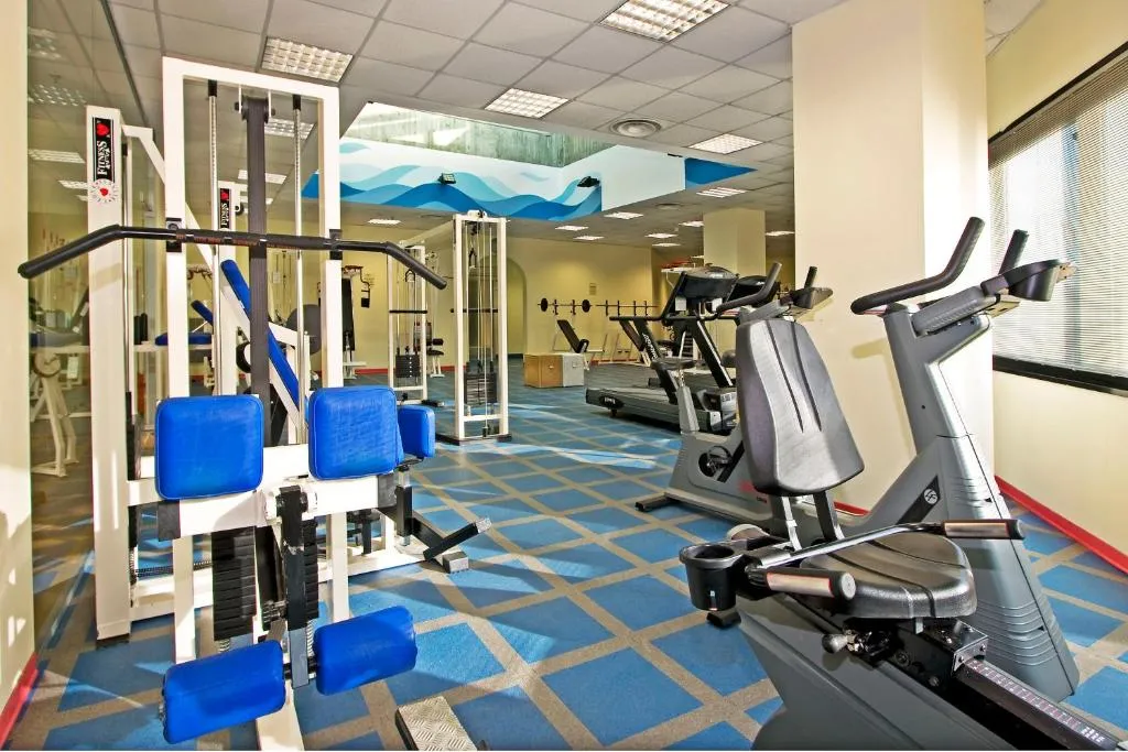 Palestra attrezzata con macchinari per cardio e pesi su pavimento azzurro