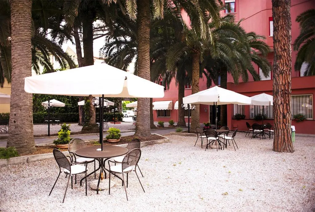Giardino esterno con tavoli, sedie e ombrelloni bianchi tra le palme