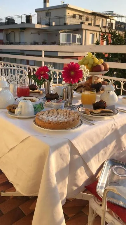 Colazione servita in terrazza con crostata, dolci, frutta e fiori
