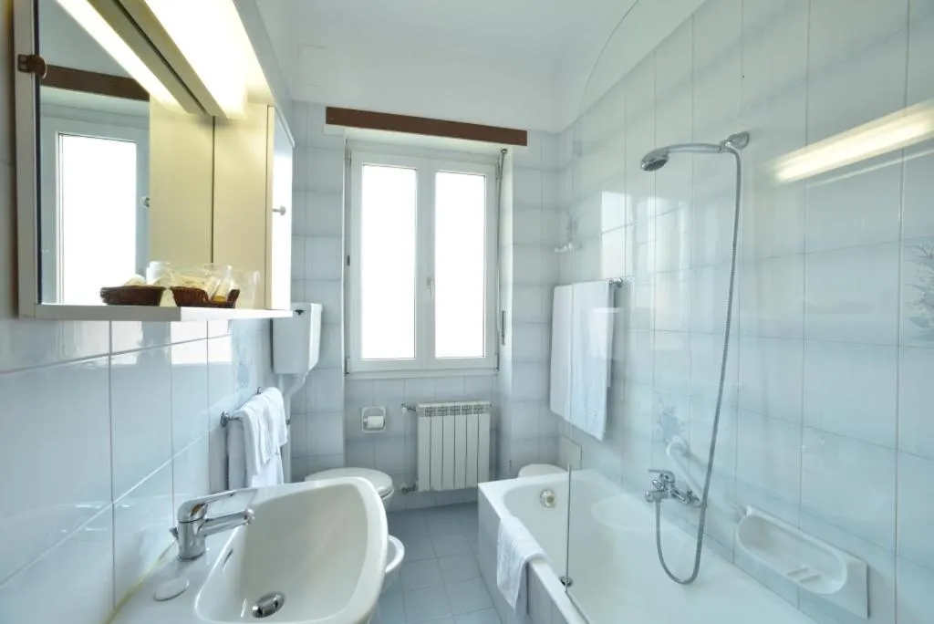 Bagno luminoso con vasca, doccia, lavabo e finestra