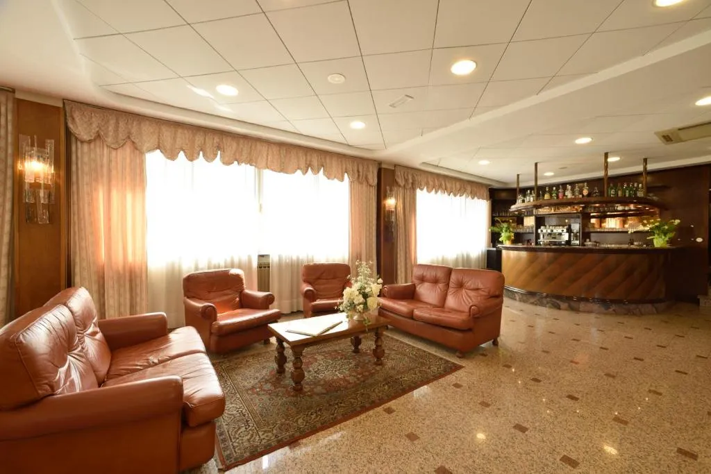 Hall dell'hotel con poltrone in pelle marrone, tavolino e bar sullo sfondo