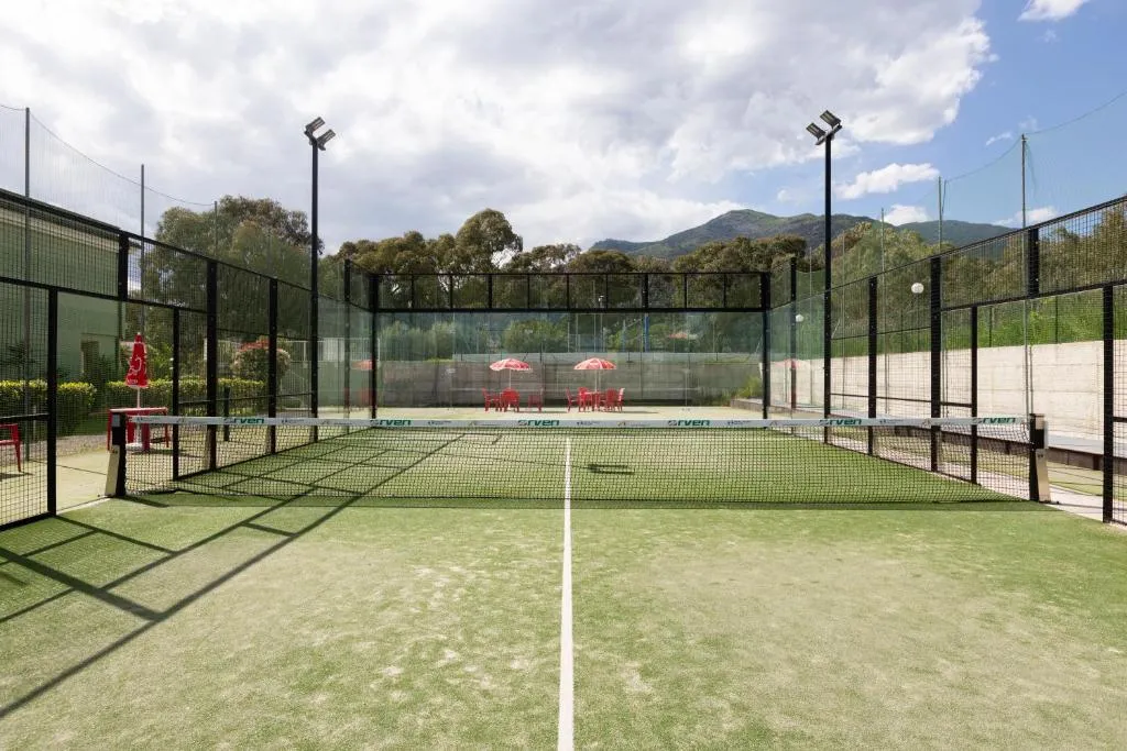 Campo da padel in erba sintetica con illuminazione e montagne sullo sfondo