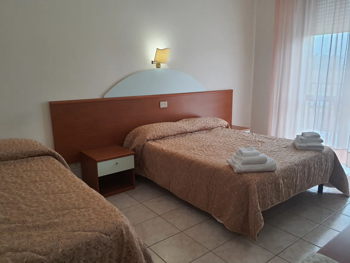 Camera con letto matrimoniale e letto singolo, comodino e finestra