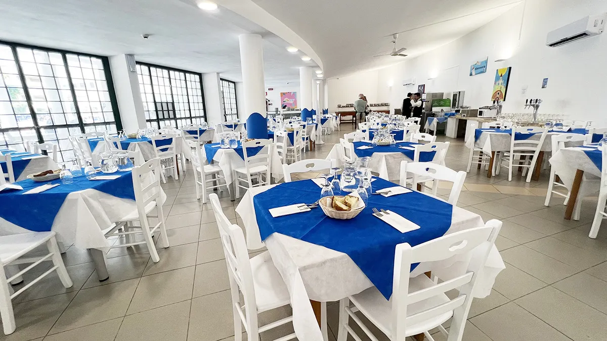 Sala ristorante interna con tavoli bianchi e blu e ampie vetrate