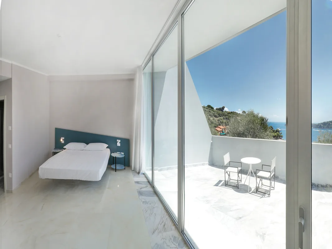 Camera moderna con letto sospeso, ampie vetrate e terrazza con vista sul mare