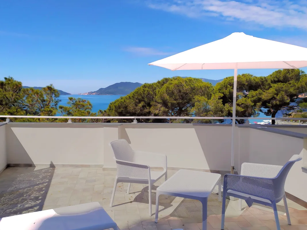 Terrazza privata con poltrone bianche, ombrellone e vista panoramica sul golfo