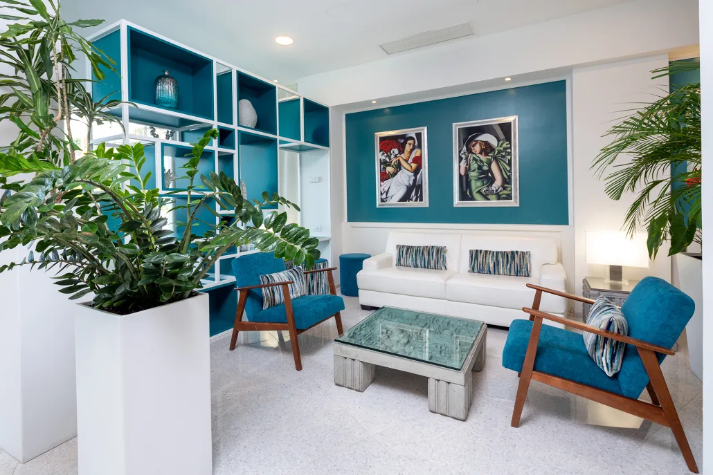Elegante area lounge della hall con poltrone blu, divano bianco e quadri decorativi