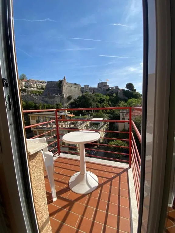 Balcone con tavolino bianco e vista su castello e collina sotto cielo azzurro