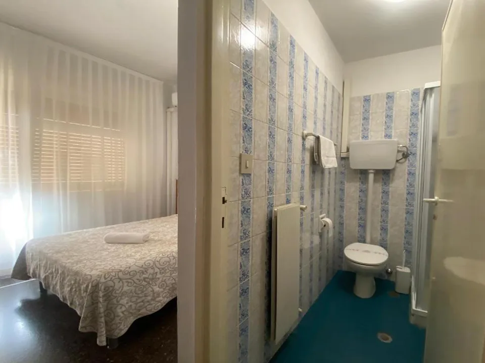 Camera con letto matrimoniale e bagno con piastrelle bianche e azzurre