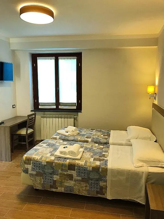 Camera da letto moderna con due letti, scrivania e TV a parete