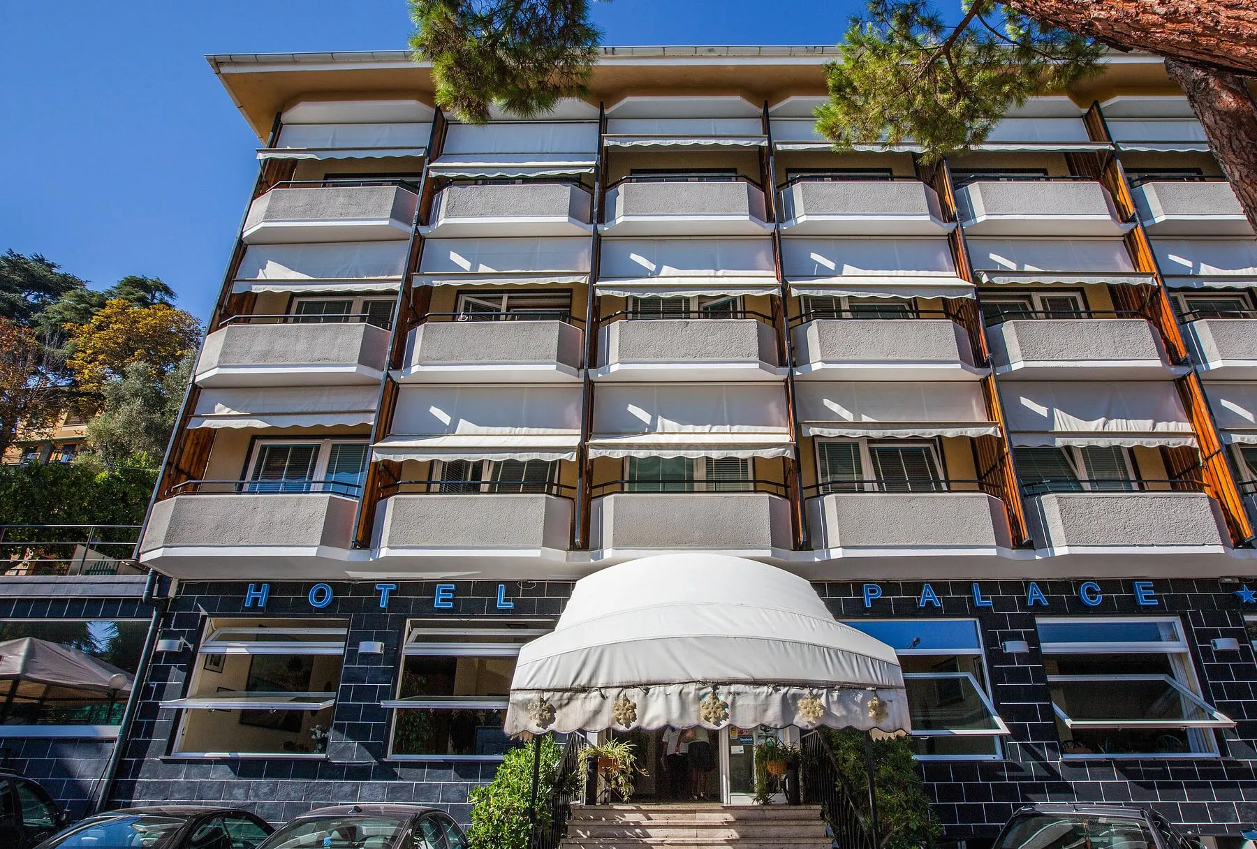 Facciata dell'hotel Palace con balconi, tende parasole e ingresso con pensilina