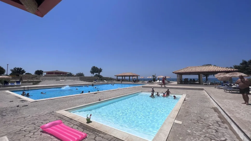 Piscine esterne con bagnanti, gazebo e vista mare in una giornata di sole