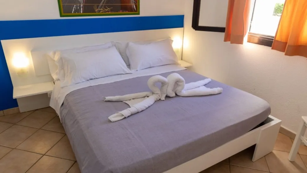 Camera da letto con letto matrimoniale, testiera blu e bianca e asciugamani decorativi