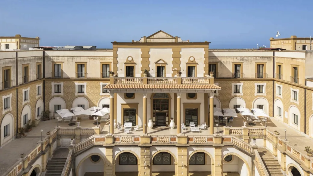 Corte interna dell'edificio storico con terrazza panoramica e ombrelloni bianchi