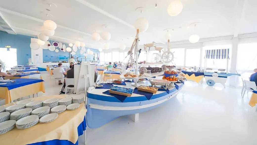 Sala ristorante in stile marino con buffet a forma di barca, decorazioni blu e gialle