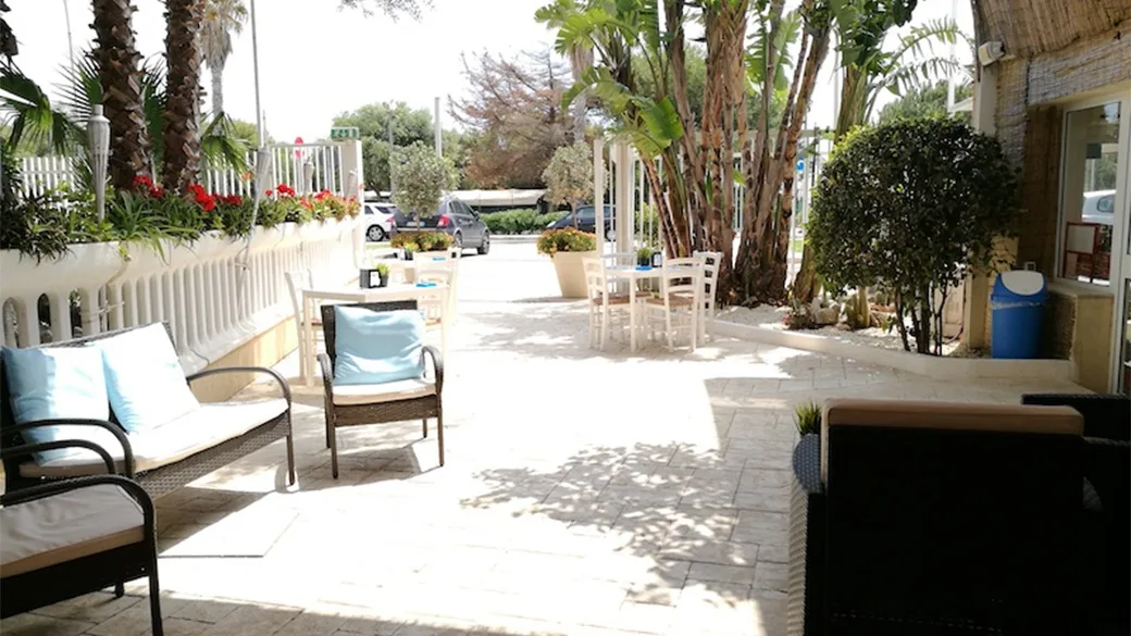 Area relax esterna con divani imbottiti e tavolini tra le palme