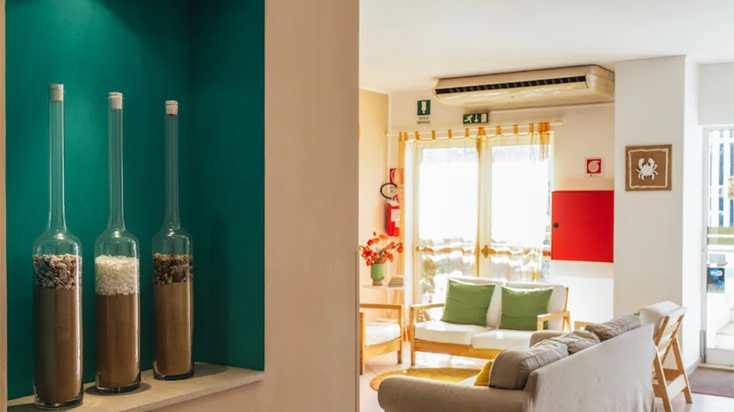Area comune con divani, decorazioni in vetro e parete verde