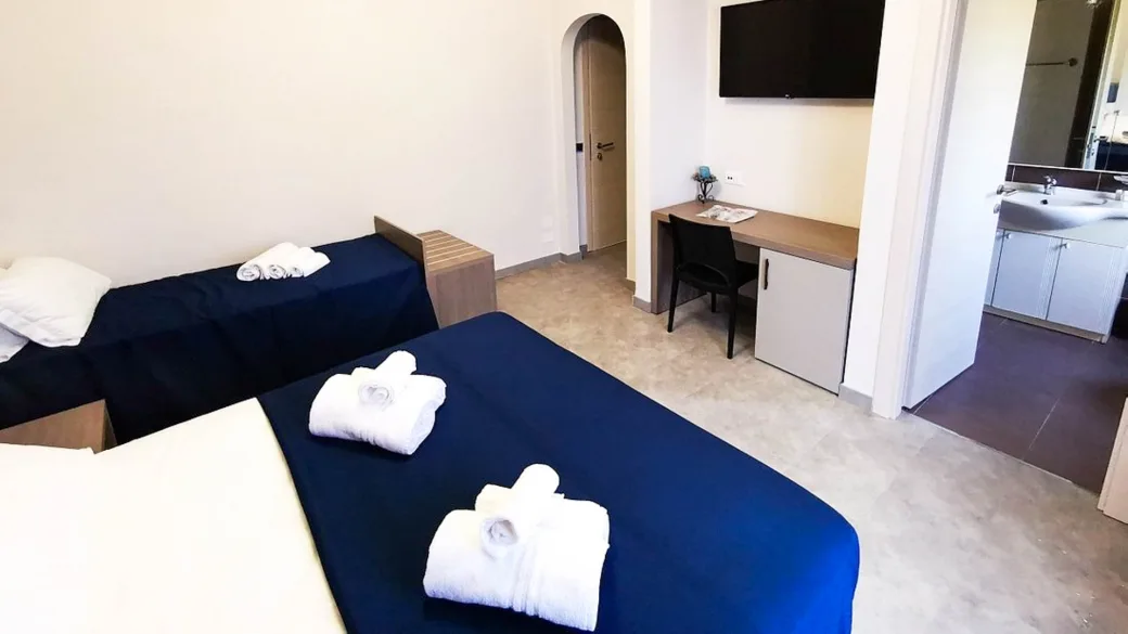 Camera con due letti, scrivania, TV a parete e bagno con lavabo